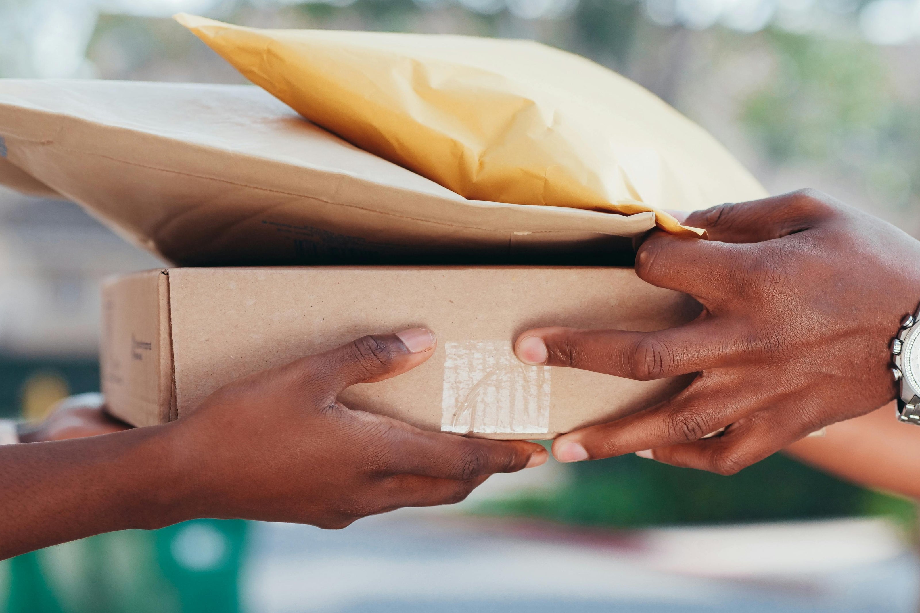 Two hands exchanging a package with a blurred background